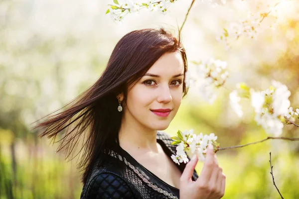 Retrato de cerca de la joven morena con flor de cerezo en —  Fotos de Stock