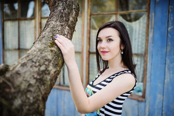 Brunette fille modèle à robe avec des rayures posées près de l'arbre . — Photo