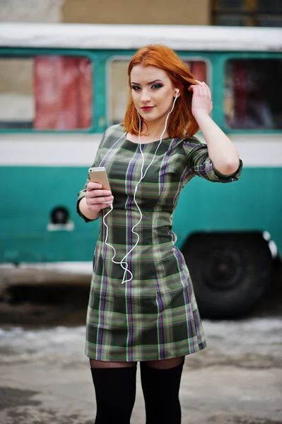 Молодая рыжая девушка с мобильным телефоном и наушниками — стоковое фото