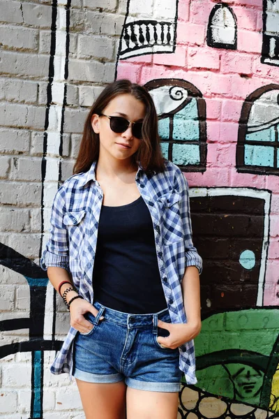 Porträtt av vacker tonårsflicka i solglasögon slitna på check — Stockfoto