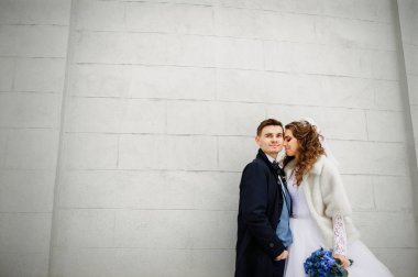 Soğuk kış günü beyaz taş duvara genç düğün çifte