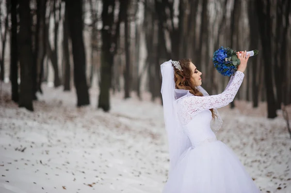 Hübsche junge Braut mit blauem Hochzeitsstrauß am Wintertag auf dem — Stockfoto