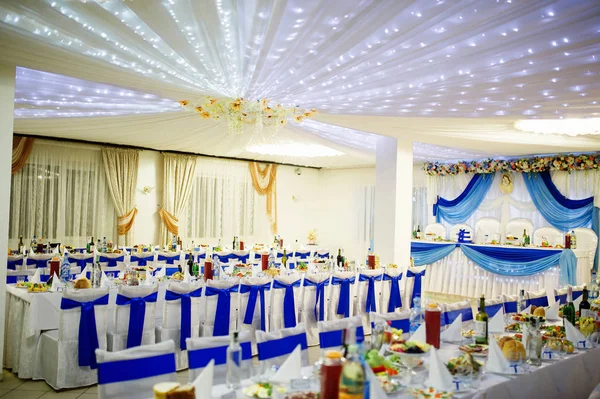 Bruiloftszaal met stoelen en tafel met blauwe linten. — Stockfoto