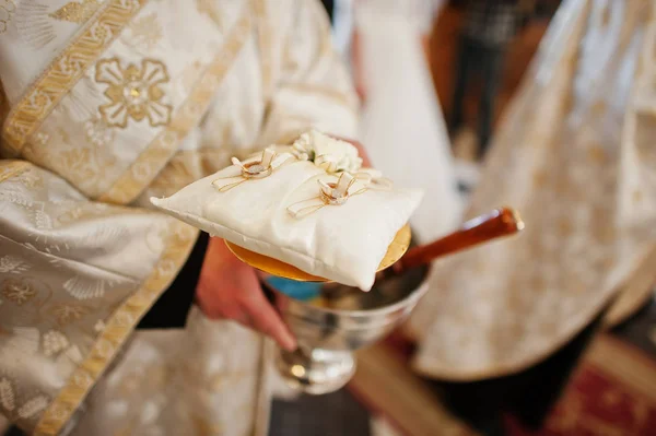 Priester hält bei kirchlicher Zeremonie ein kleines Kissen mit Trauringen — Stockfoto