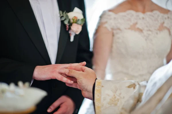 Prêtre met bague de mariage à la main des mariés à l'église . — Photo