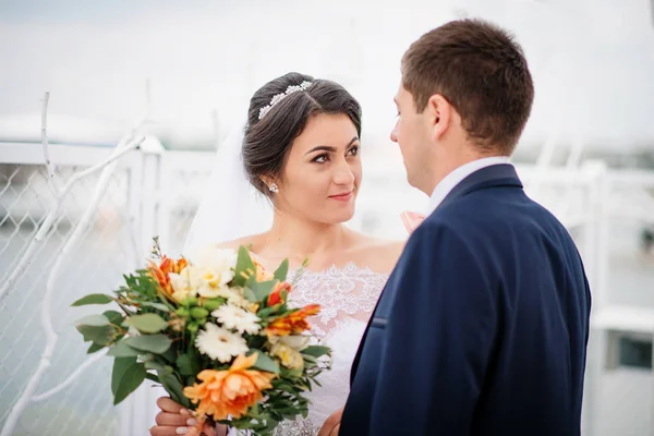 Esküvői pár marad a pier kikötő felhős napon. — Stock Fotó