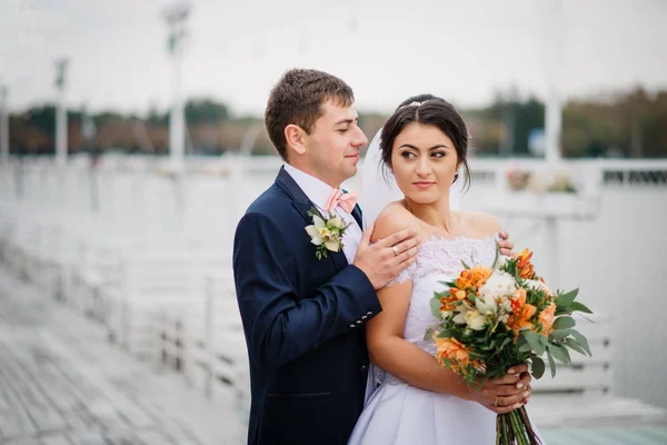 Esküvői pár marad a pier kikötő felhős napon. — Stock Fotó