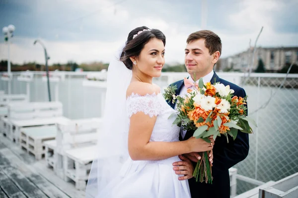 Bruidspaar verblijven op de pier ligplaats bewolkte dag. — Stockfoto