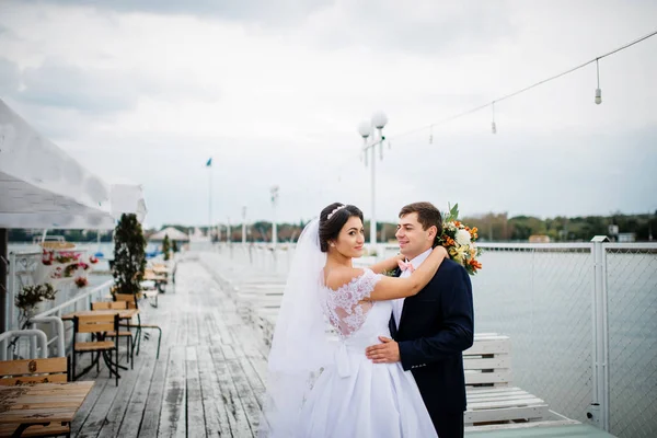 Wedding couple stay on the pier berth at cloudy day. — Stock Photo, Image