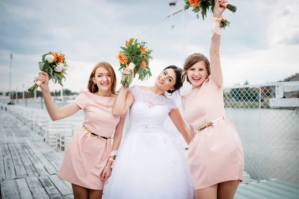 Sposa con damigelle posato sul molo ormeggio al matrimonio nuvoloso — Foto Stock