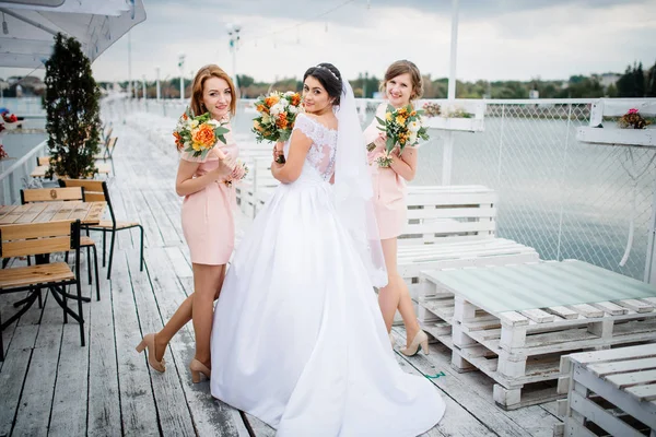 Невеста с подружками невесты позировала на причале на облачной свадьбе — стоковое фото