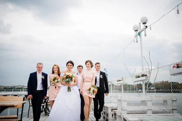 Hochzeitspaar mit Brautjungfern und Trauzeugen übernachtet auf der Seebrücke — Stockfoto