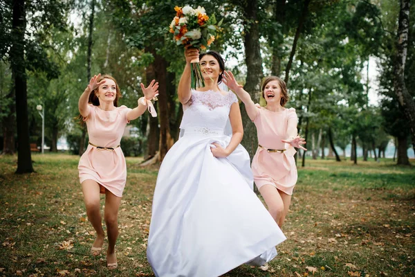 Braut mit Brautjungfern werfen Strauß am Hochzeitstag. — Stockfoto