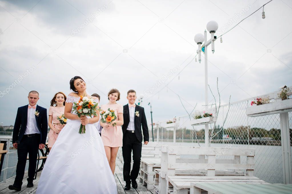 Wedding couple with bridesmaids and best mans stay on the pier b