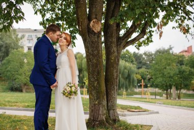 Düğün çifti, bulutlu gün arka plan ağaç aşık.