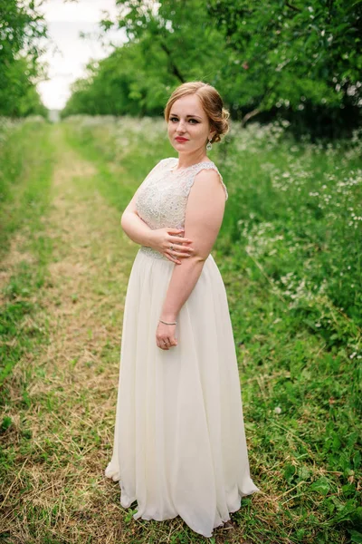 Joven chica con sobrepeso en vestido beige posado fondo primavera gar —  Fotos de Stock