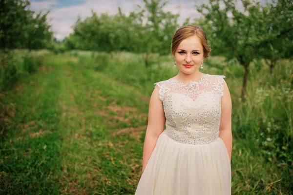 Joven chica con sobrepeso en vestido beige posado fondo primavera gar — Foto de Stock