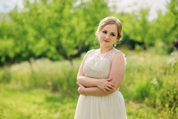 Joven chica con sobrepeso en vestido beige posado fondo primavera gar — Foto de Stock