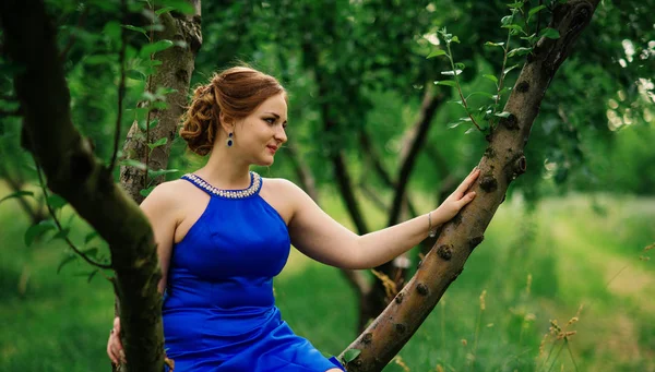 Ung överviktig tjej på blå klänning poserade bakgrund våren gard — Stockfoto