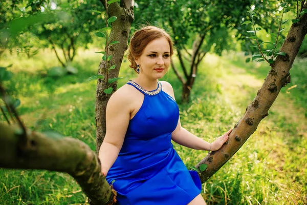 Joven chica con sobrepeso en vestido azul posado fondo primavera gard —  Fotos de Stock