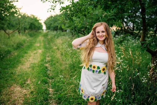 Junges Mädchen im ukrainischen Nationalkleid posierte im Frühlingsgarten. — Stockfoto