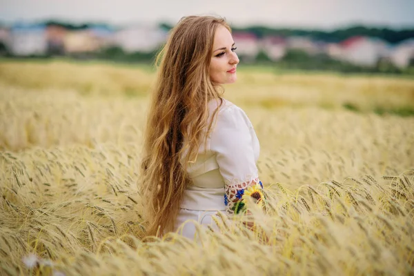 Jeune fille à la robe nationale ukrainienne posée au champ de couronnes . — Photo