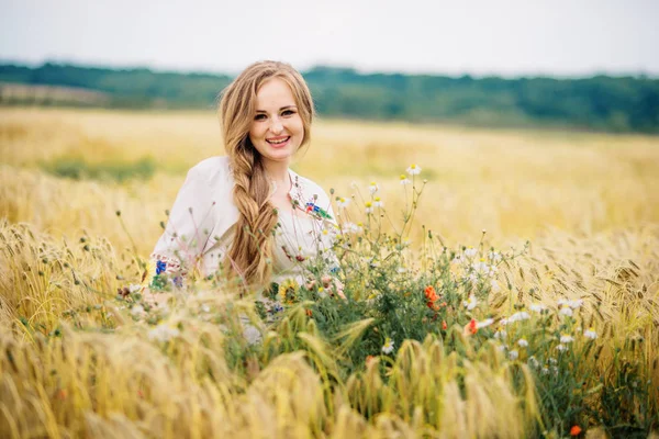 Jeune fille à la robe nationale ukrainienne posée au champ de couronnes . — Photo