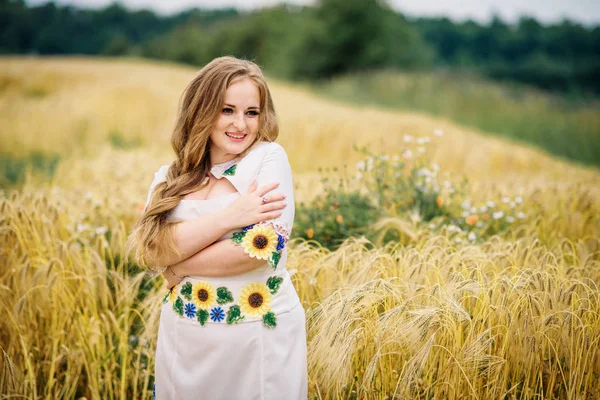 Jong meisje op de Oekraïense nationale jurk gesteld bij krans veld. — Stockfoto