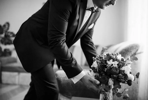 Жених со свадебным букетом в его комнате в утренний день. Черный и — стоковое фото