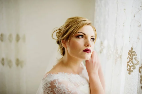 Noiva loira em um roupão de banho no dia do casamento perto de cortinas em seu r — Fotografia de Stock