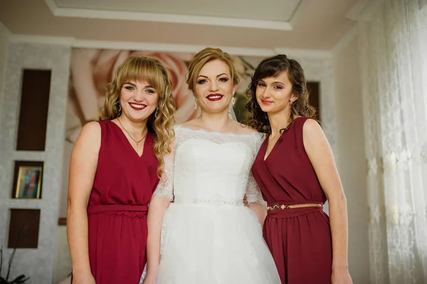Lächelnde Braut mit Brautjungfern auf roten Kleidern im Innenraum. — Stockfoto