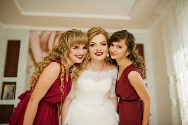 Усміхнена наречена з подружками на червоних сукнях в приміщенні . — стокове фото
