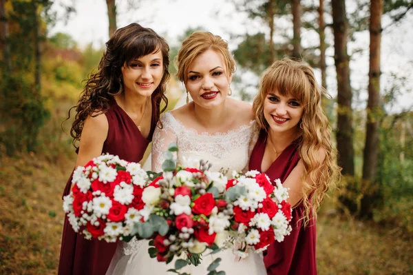 Braut mit Brautjungfern auf roten Kleidern im Herbst. — Stockfoto
