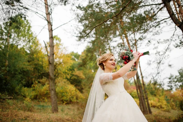 Blonde bride with wedding bouquet and bright make up at autumn p — Stock Photo, Image