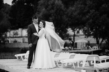 Büyüleyici Düğün çifti dock iskelede sarılma. Siyah ve w