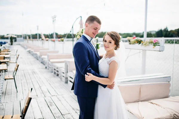Charmantes Hochzeitspaar umarmt sich auf der Seebrücke des Docks. — Stockfoto