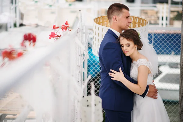 Encantadora pareja de boda abrazándose en el muelle del muelle . — Foto de Stock