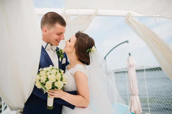 Очаровательная свадебная пара обнимается на пирсе дока под бунгалом — стоковое фото