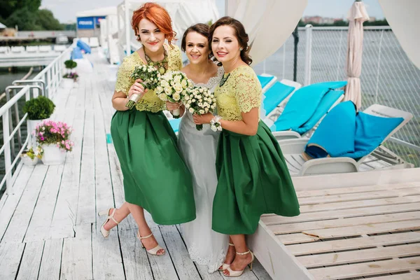 Bruid met de bruidsmeisjes plezier op pier in de buurt van lake. — Stockfoto