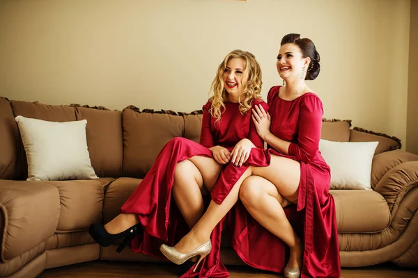 Zwei sexy Brautjungfern zeigen ihre Beine aus roten Kleidern bei der Hochzeit — Stockfoto