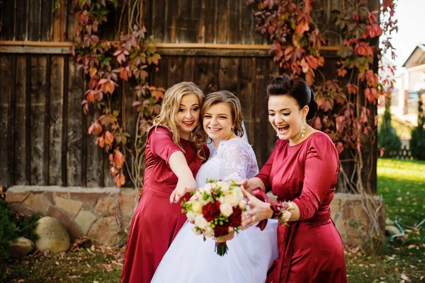Noiva com damas de honra fundo velho casa de madeira com folhas vermelhas — Fotografia de Stock