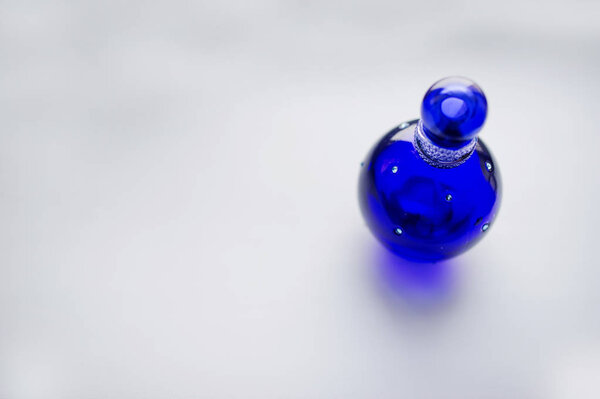Blue glass pin like perfume on white background.