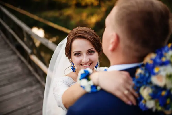 Fröhliches Hochzeitspaar auf Holzbrücke bei Sonnenuntergang. — Stockfoto