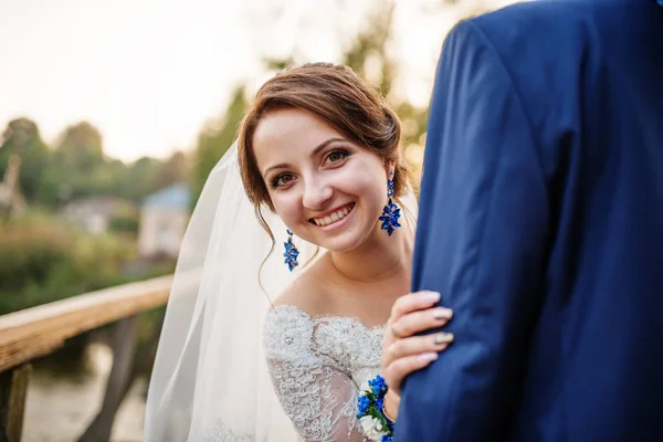 Fröhliches Hochzeitspaar auf Holzbrücke bei Sonnenuntergang. — Stockfoto