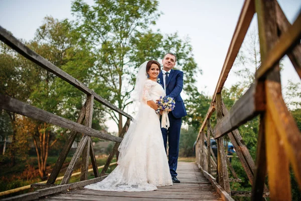 Casal alegre na ponte de madeira ao pôr-do-sol . — Fotografia de Stock