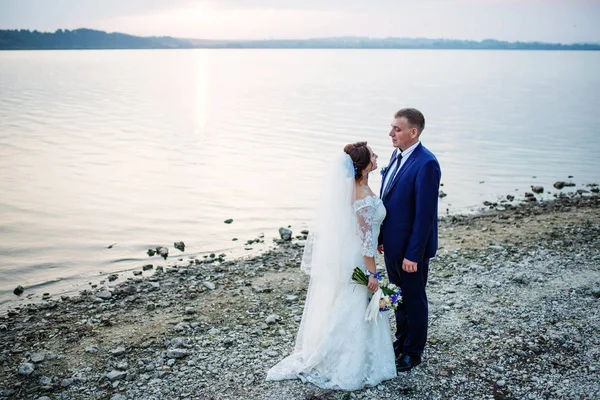 Jonggehuwden verliefd in de buurt van rivier op zonsondergang op hun awesome bruiloft — Stockfoto