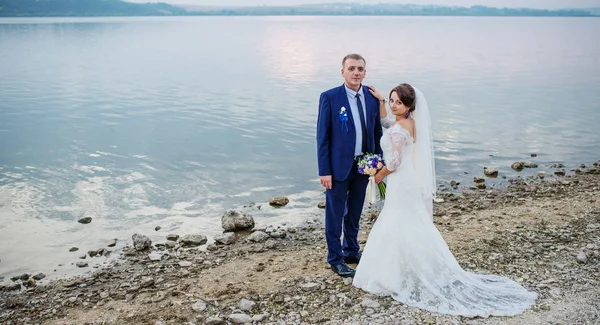 Frisch verliebte Brautpaare am Fluss bei Sonnenuntergang auf ihrer fantastischen Hochzeit — Stockfoto