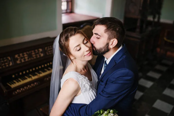 Casal de casamento adorável abraçando na antiga sala antiga perto da janela . — Fotografia de Stock