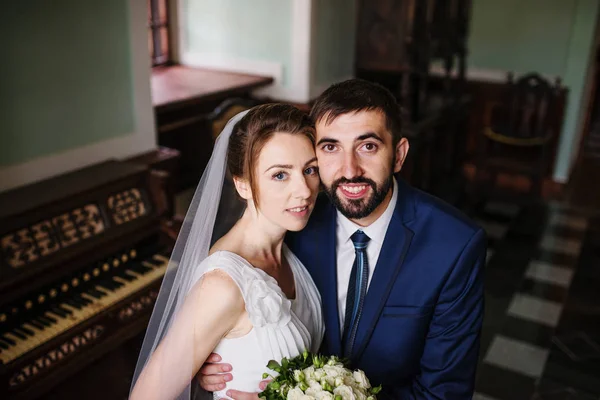 Casal de casamento adorável abraçando na antiga sala antiga perto da janela . — Fotografia de Stock