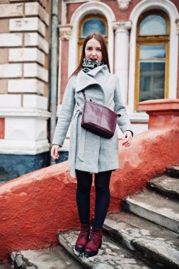 Genç kız deri çanta ile gri paltolu omzuna model.